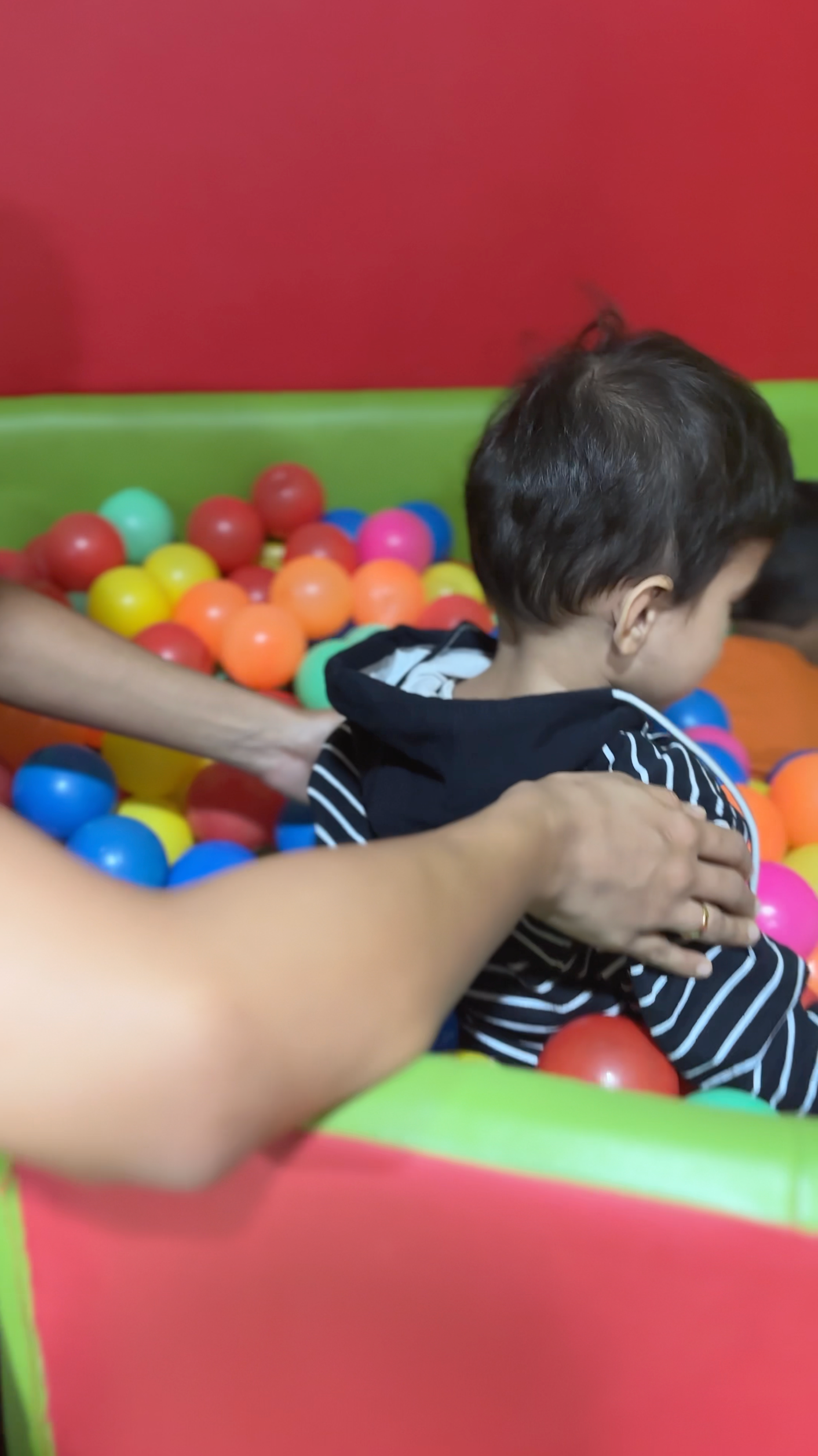 A child receiving guided sensory play therapy in a colorful ball pit, supported by a therapist.